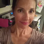 A woman in a home kitchen environment looking calmly at the camera.