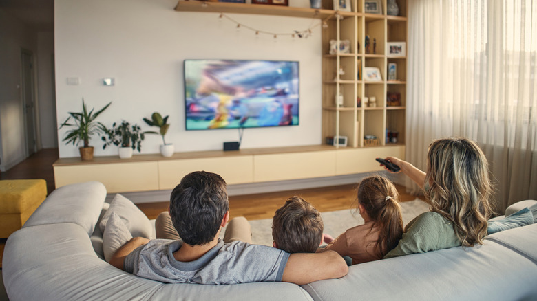 A family sitting together on a sofa watching a vibrant movie on a large Samsung 4K TV.