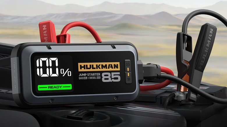 Hulkman Alpha 85 jump starter connected to a car battery showing the digital screen.