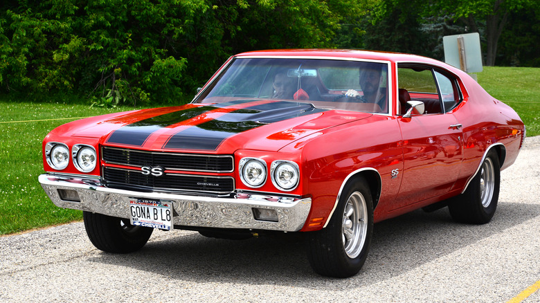 A red 1970 Chevrolet Chevelle SS 454 being driven, highlighting its muscular profile.