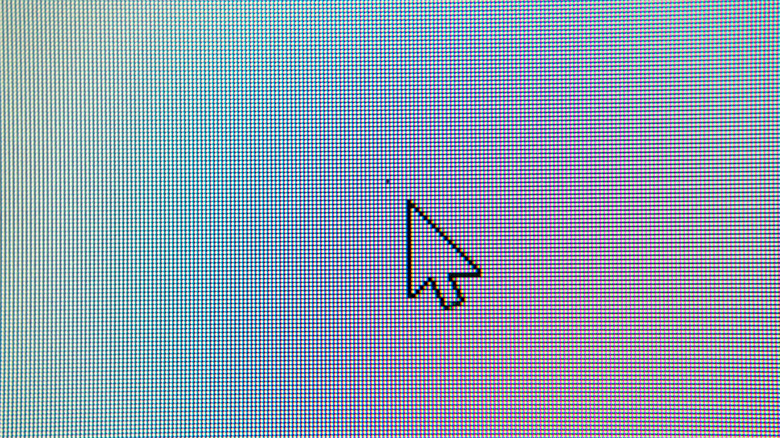 A white mouse cursor on a bright screen pointing directly at a single black dot representing a dead pixel.