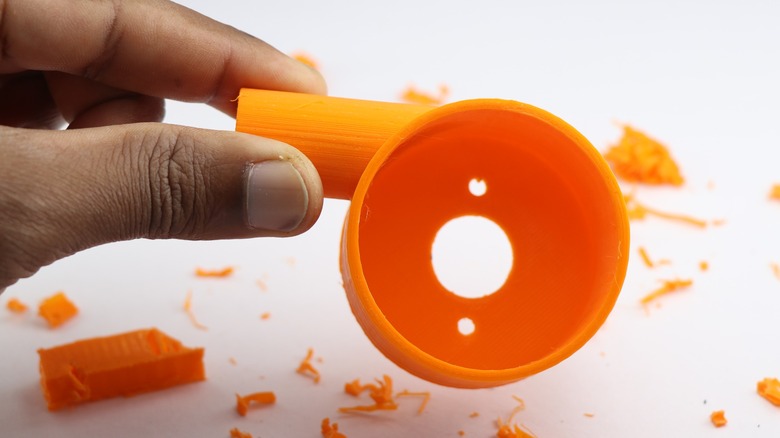Close-up of a hand holding a finished 3D printed object showcasing structural integrity.