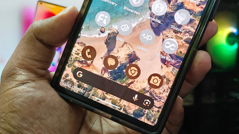 A person holding a smartphone with the words Safe Mode displayed on the bottom left of the screen.