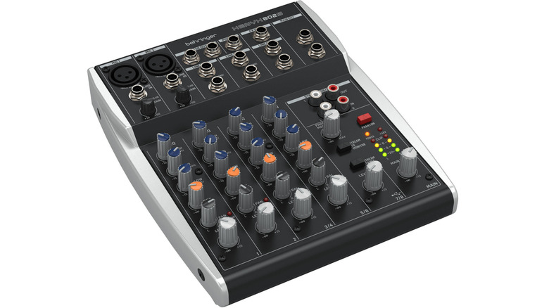 Behringer XENYX 802S compact analog mixer showing gold-plated XLR inputs and blue-capped knobs.