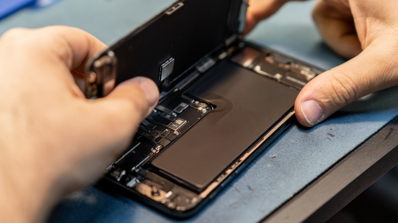 A high-angle view of an opened smartphone showing its internal battery and protective plates.