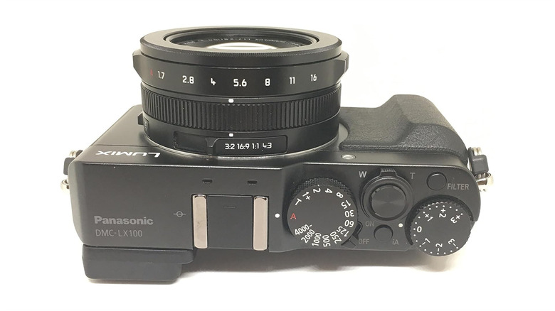 The front view of a black Panasonic Lumix LX100 camera showing its Leica lens.