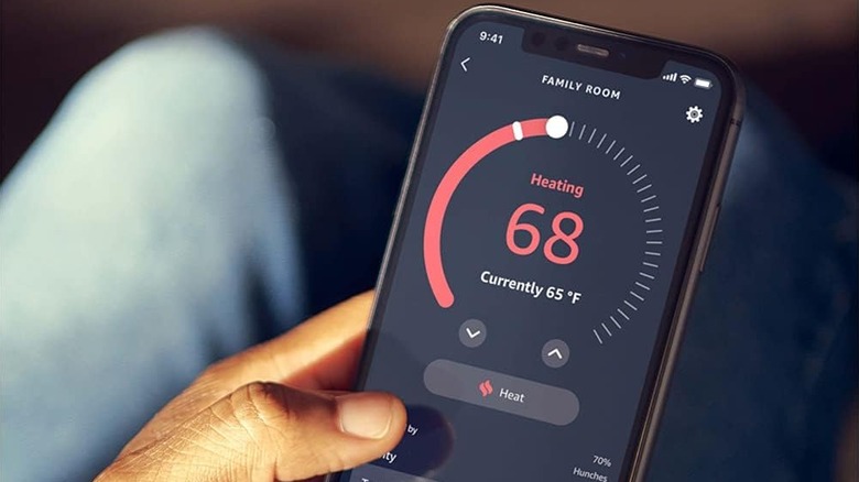 A person using the Alexa mobile app to adjust the temperature settings of a smart thermostat.