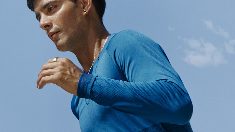 A man in a blue shirt running outdoors while wearing an Oura Ring 4.