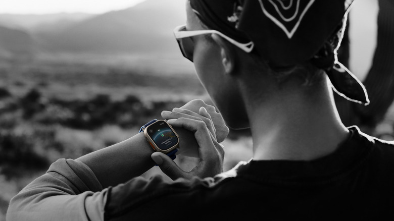 A person using an Apple Watch Ultra 3 to access satellite connectivity features in an outdoor setting.