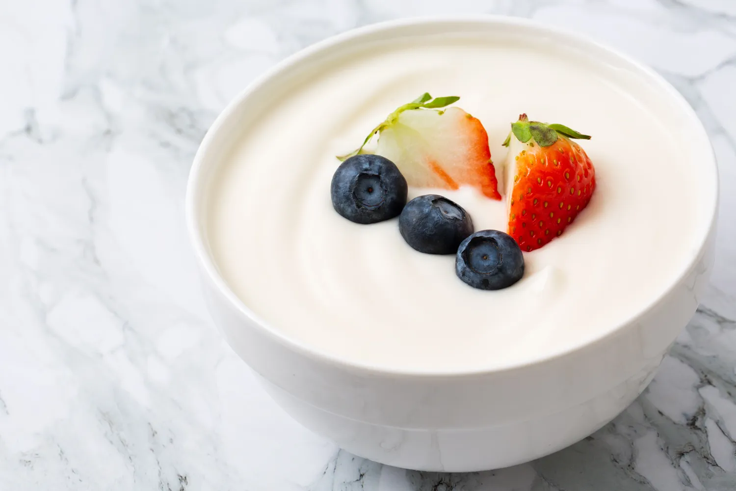 A bowl of thick Greek yogurt topped with fresh berries.