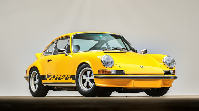 A yellow 1973 Porsche 911 Carrera RS showcasing its distinctive ducktail rear spoiler.