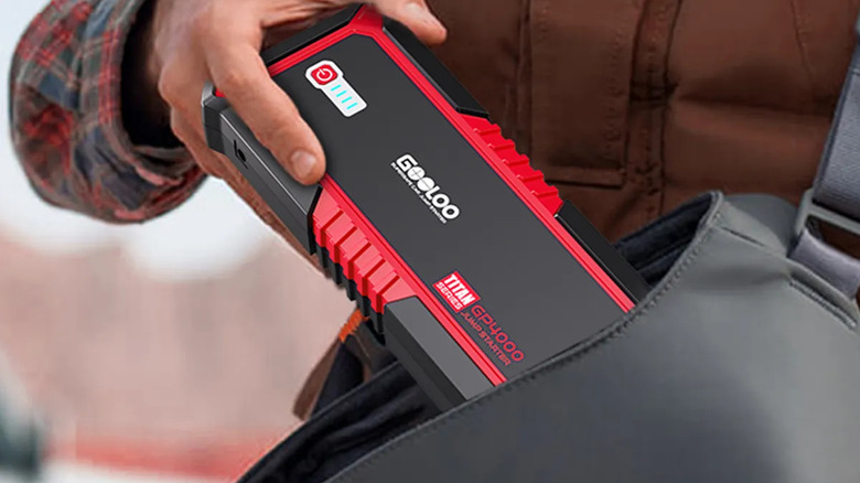A person placing a GOOLOO jump starter into its protective carrying case.