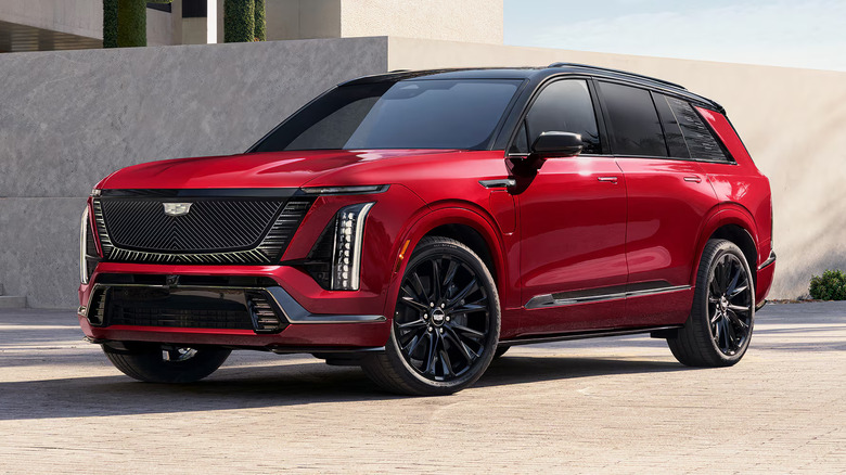 Front left view of a red Cadillac Vistiq SUV parked on a city sidewalk.