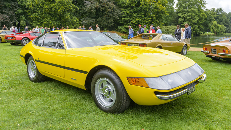 A yellow 1973 Ferrari 365 GTB/4 Daytona on display at a premium automotive event.