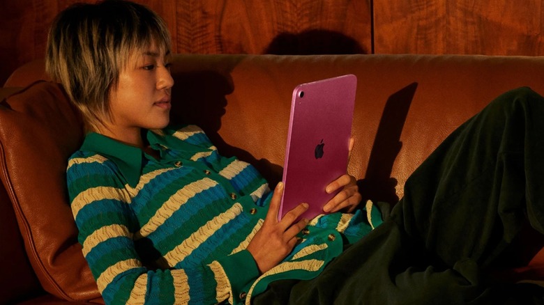 A close-up of a person using an Apple iPad on a couch.