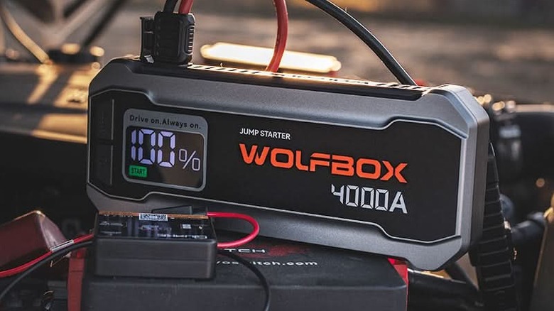 WOLFBOX MV24 jump starter with heavy-duty cables attached to a battery.