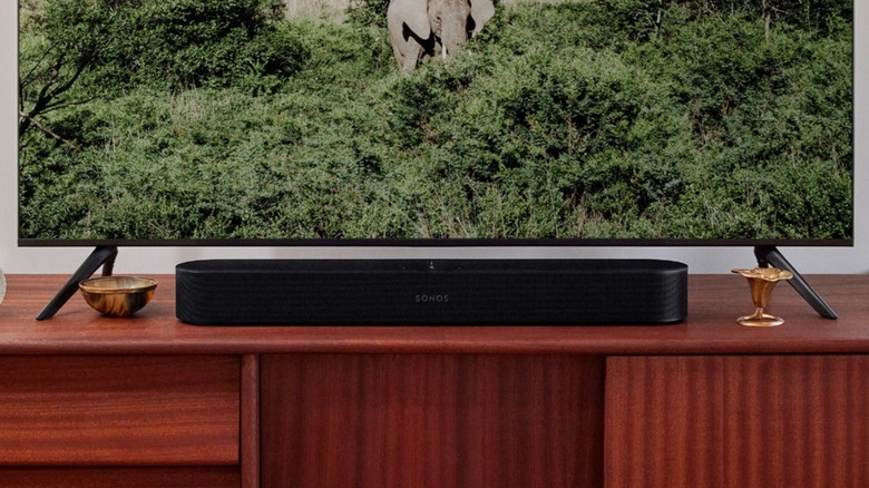 The Sonos Beam (Gen 2) soundbar placed on a wooden console in a living room setting.