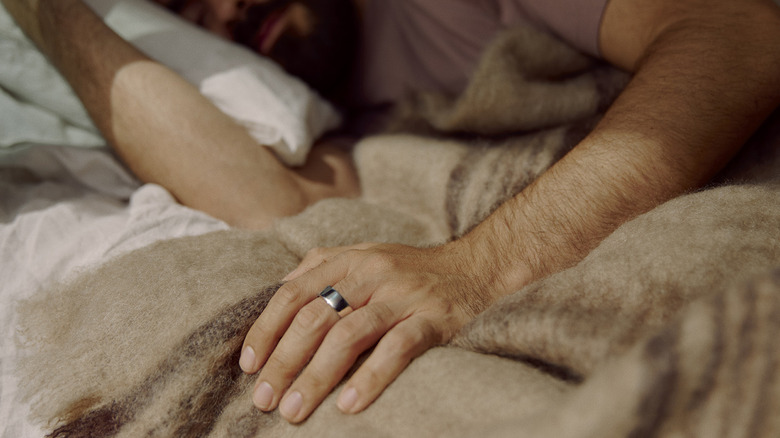 A man wearing an Oura Ring 4 while sleeping.