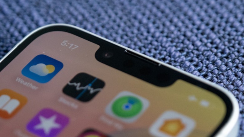 Close-up detail of the front-facing notch and top speaker of an iPhone 16e.