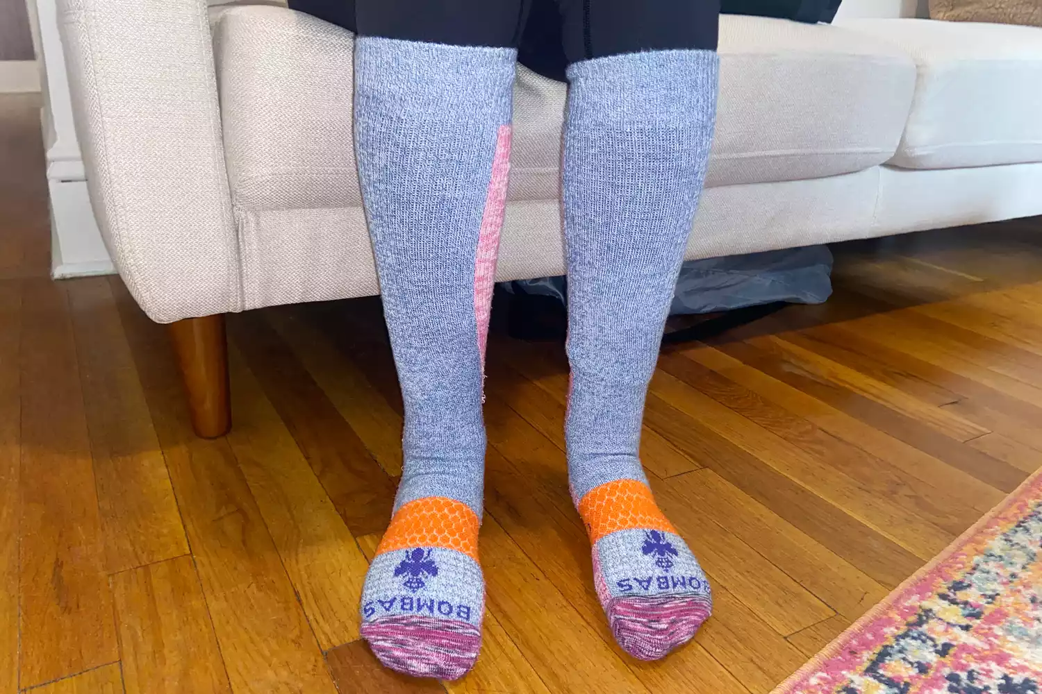A person seated comfortably on a couch wearing Bombas compression socks.