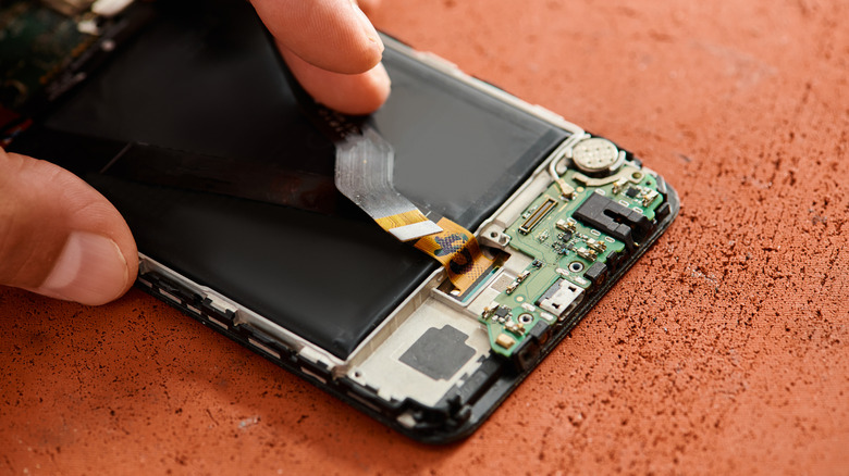 A technician carefully taking apart a smartphone to replace the damaged display unit.