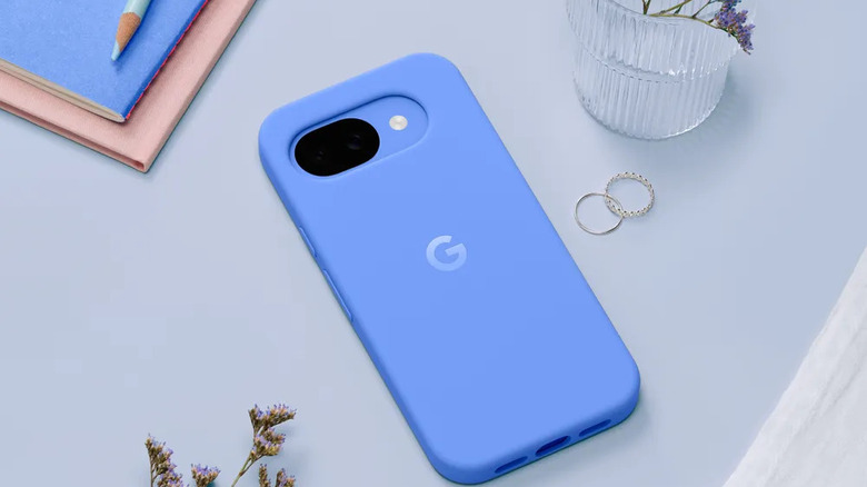 Blue Pixel 10a in a matching silicone case on a light blue surface with decorative items.